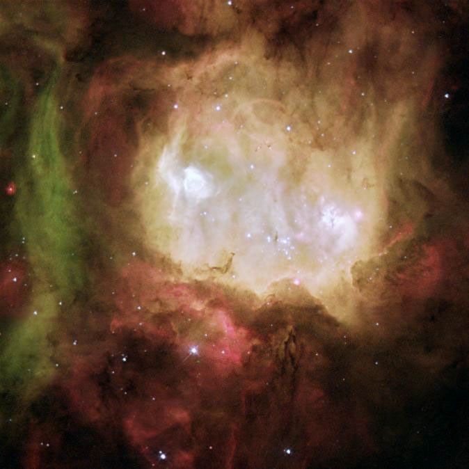 Glowing whitish center with two bright white stars glowing like eyes. Surrounded by brown, black, and red gas and dust, with a tendril of green gas on the left.